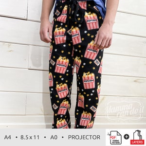 Può includere: Pantaloni da pigiama neri con stampa popcorn. I pantaloni presentano un motivo ripetuto di secchielli di popcorn con la scritta "POPCORN", insieme a stelle gialle. I pantaloni hanno un girovita con coulisse.