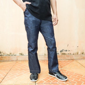 May include: A person wearing a black t-shirt and dark blue jeans with a wide leg opening. The person is wearing black shoes with white accents.