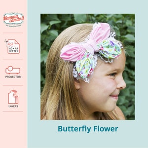 May include: A pink and blue butterfly flower hair accessory with a white lace trim. The hair accessory is worn by a young girl with blonde hair. The image includes the text "Butterfly Flower".