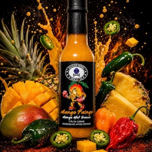 Op de afbeelding: Een fles Danger Berry Spice Co. Mango Paingo hete saus met een zwart etiket met een getekende mango met bokshandschoenen. De fles bevat 148ml oranje saus en is omringd door verse mango's, ananasstukjes en groene jalapeño pepers.