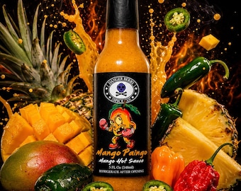 Könnte beinhalten: Eine Flasche Danger Berry Spice Co. Mango Paingo scharfe Soße mit schwarzem Etikett, das eine gezeichnete Mango mit Boxhandschuhen zeigt. Die Flasche enthält 148ml orangefarbene Soße, umgeben von frischen Mangos, Ananasstücken und grünen Jalapeño-Chilis.