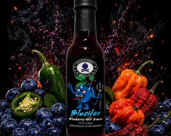 May include: A glass bottle of Blucifer Blueberry Hot Sauce with a black label featuring a blue cartoon character, a skull logo, and the text Danger Berry Spice Co. The bottle is surrounded by fresh blueberries, green jalapeños, and orange habanero peppers.