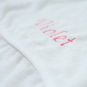 May include: White towel with the word "Violet" embroidered in pink.