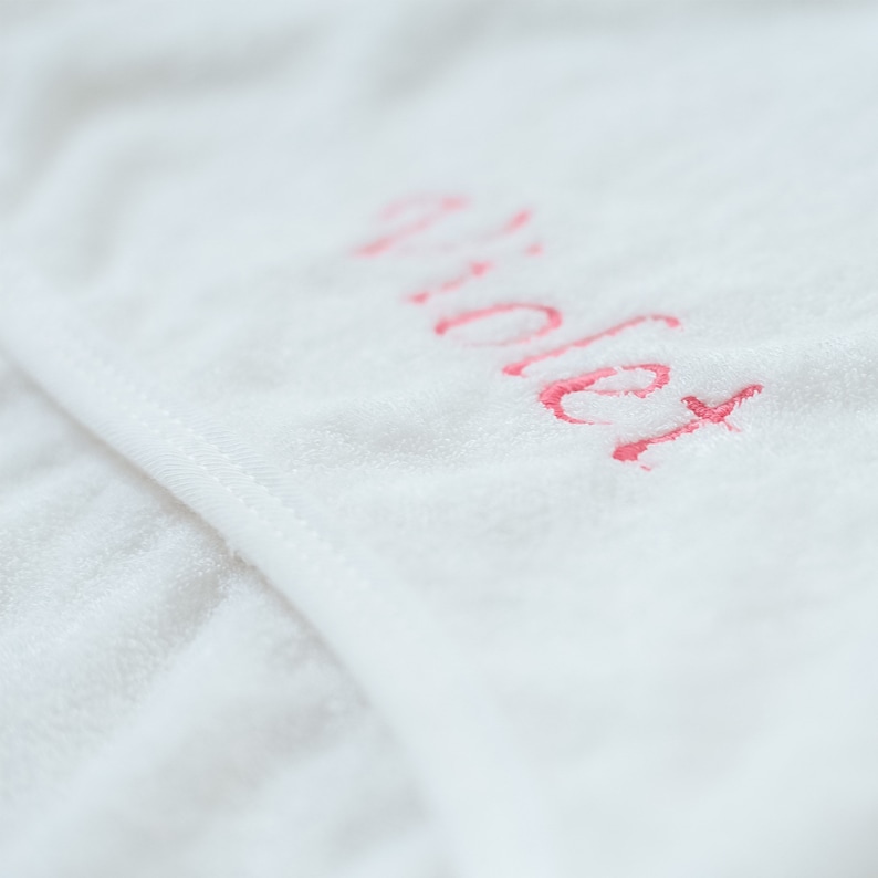 May include: White towel with the word "Violet" embroidered in pink.