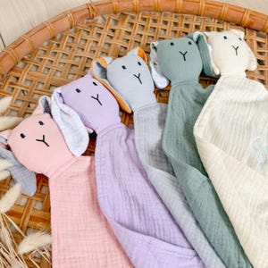 May include: Four plush bunny security blankets in different colors: pink, lavender, gray, and cream. Each bunny has a white embroidered Y on its chest.