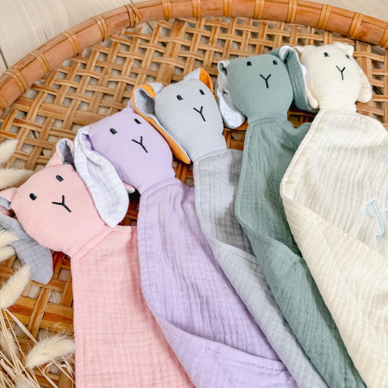 May include: Four plush bunny security blankets in different colors: pink, lavender, gray, and cream. Each bunny has a white embroidered Y on its chest.