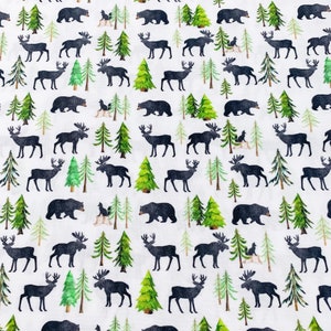 May include: A white fabric with a repeating pattern of black moose, deer, bears, and pine trees. The pattern is a woodland theme.