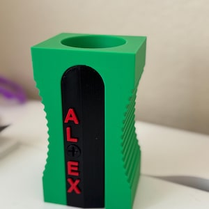 May include: A green pencil sharpener with a black blade and the word "ALEX" printed in red letters on the side.