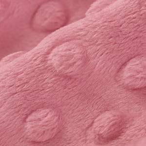 May include: Close-up of a soft, pink fabric with a textured, dotted pattern. The fabric is plush and has a subtle sheen.