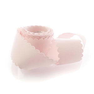 May include: A roll of light pink grosgrain ribbon featuring a scalloped edge design. The ribbon has a distinct ribbed texture running horizontally along its length, and a small white label with black text is visible on the inner core of the roll.