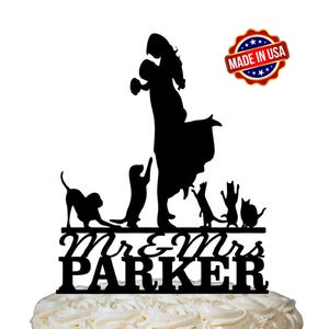 May include: Black silhouette cake topper of a couple holding hands with a dog and two cats. The topper says "Mr. & Mrs. Parker" and "Made in USA".