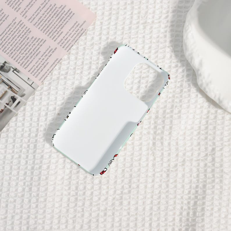Puede incluir: Una funda de tel&eacute;fono blanca con un borde azul claro y un patr&oacute;n de peque&ntilde;os corazones rojos. La funda tiene recortes para la c&aacute;mara y los botones, y est&aacute; dise&ntilde;ada para proteger el tel&eacute;fono.