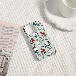 Puede incluir: Una funda de tel&eacute;fono azul claro con un patr&oacute;n repetido de personajes de dibujos animados, incluyendo un gato con un lazo rojo, un conejito y otros dise&ntilde;os lindos. La funda tiene recortes para la c&aacute;mara y los botones.