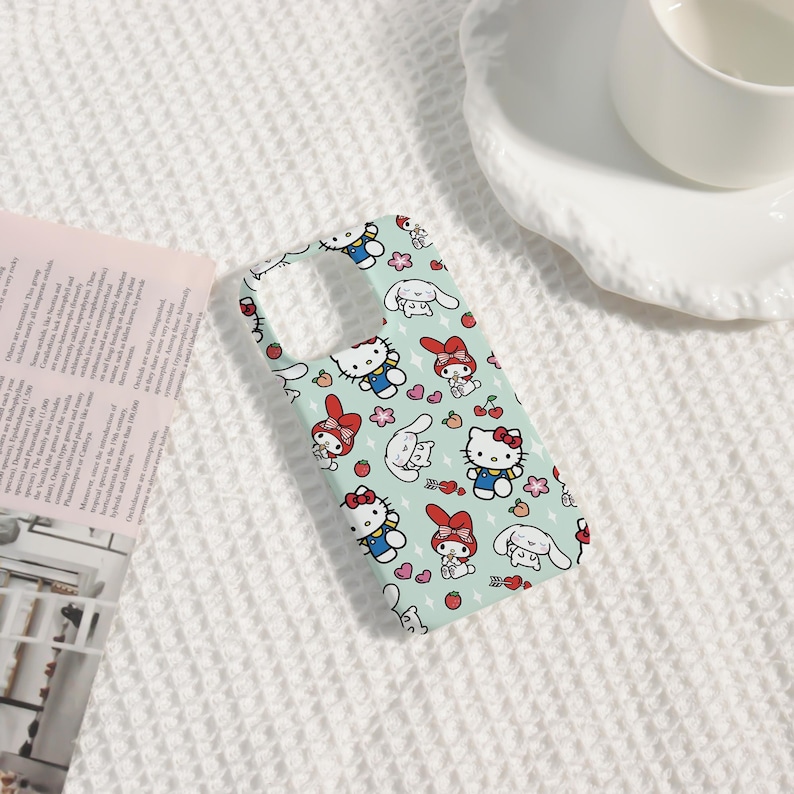 Puede incluir: Una funda de tel&eacute;fono azul claro con un patr&oacute;n repetido de personajes de dibujos animados, incluyendo un gato con un lazo rojo, un conejito y otros dise&ntilde;os lindos. La funda tiene recortes para la c&aacute;mara y los botones.