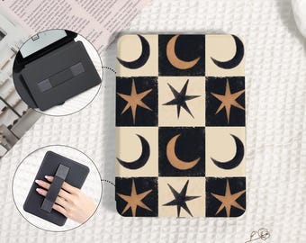 May include: A black tablet case with a celestial design featuring moons and stars in a grid pattern. The case has a built-in hand strap for secure holding. The design includes cream, black, and gold colours.