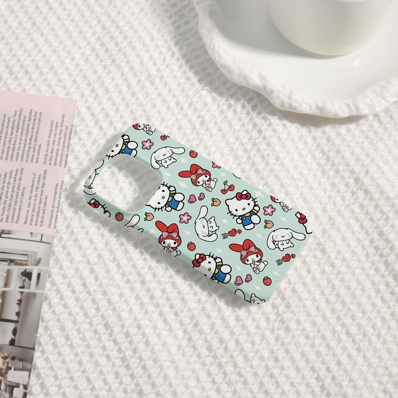 Puede incluir: Funda de tel&eacute;fono azul claro con un patr&oacute;n repetido de personajes de dibujos animados, incluyendo un gato con un lazo rojo, un conejo blanco, flores y fresas. La funda est&aacute; dise&ntilde;ada para un smartphone.