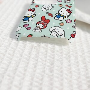 Puede incluir: Una funda de tel&eacute;fono azul claro con personajes de dibujos animados como Hello Kitty, My Melody y Cinnamoroll. La funda tiene un patr&oacute;n repetido de los personajes, corazones, fresas y flores. La funda est&aacute; hecha de un material liso.