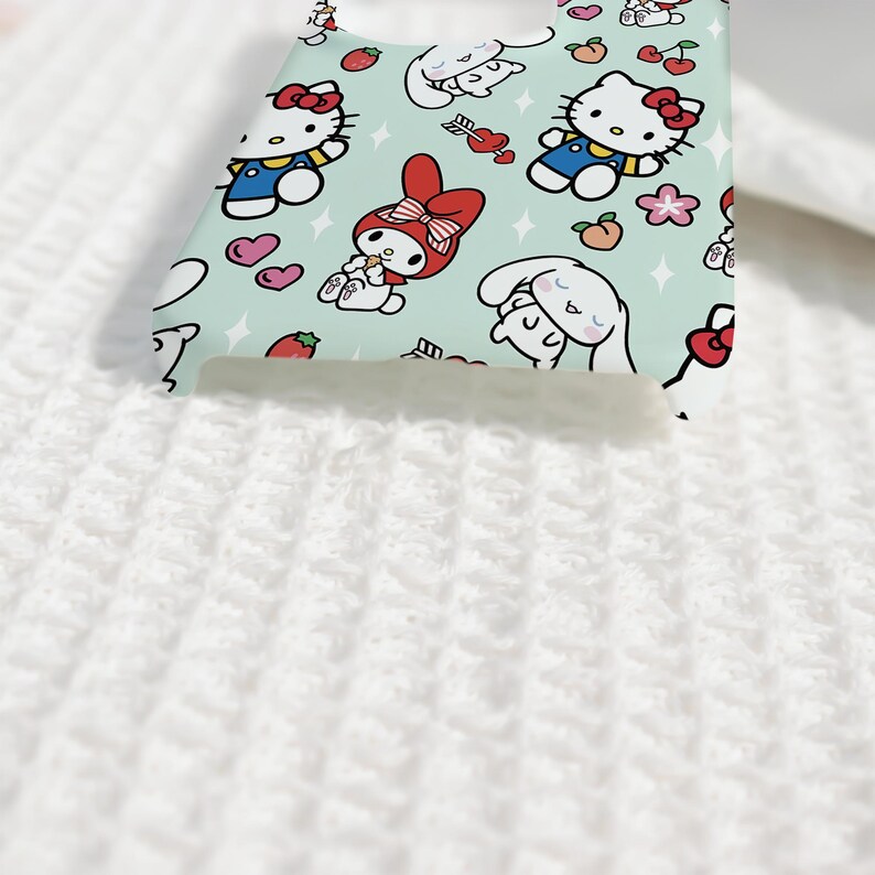 Puede incluir: Una funda de tel&eacute;fono azul claro con personajes de dibujos animados como Hello Kitty, My Melody y Cinnamoroll. La funda tiene un patr&oacute;n repetido de los personajes, corazones, fresas y flores. La funda est&aacute; hecha de un material liso.