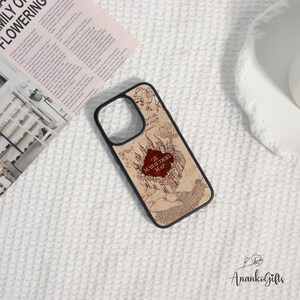 May include: A black phone case featuring a map design with the text "The Marauders Map" in a red oval. The map is in shades of brown and beige, with a castle illustration. The case is on a white textured surface.