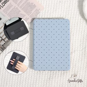 May include: A light blue tablet case with a black polka dot pattern. The case has a built-in hand strap for easy holding. A black tablet stand is also shown. The brand name "AnankoGifts" is visible.