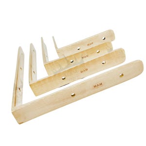 May include: A set of unfinished wooden shelf brackets, each with a right-angle design. The brackets are light-coloured, with pre-drilled holes for mounting. The text "MAM" is printed on each bracket.