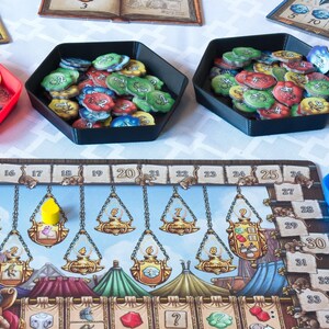 Könnte beinhalten: Ein Brettspiel mit einem farbenfrohen Spielbrett, roten, blauen und schwarzen Tabletts und verschiedenen Spielsteinen. Das Spielbrett zeigt ein mittelalterliches Design mit einem Charakter, einer Reihe von Waagen und nummerierten Feldern.