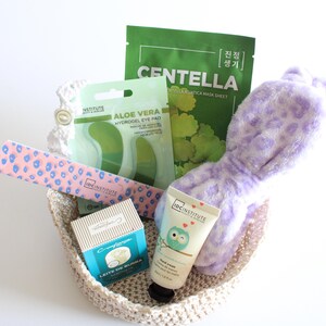 Pu&ograve; includere: Un cestino intrecciato beige pieno di prodotti di bellezza. Include una maschera per il viso Centella verde, patch per gli occhi all'aloe vera, una lima per unghie rosa, crema per le mani e una fascia per la testa con stampa leopardata viola.