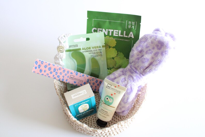 Pu&ograve; includere: Un cestino intrecciato beige pieno di prodotti di bellezza. Include una maschera per il viso Centella verde, patch per gli occhi all'aloe vera, una lima per unghie rosa, crema per le mani e una fascia per la testa con stampa leopardata viola.