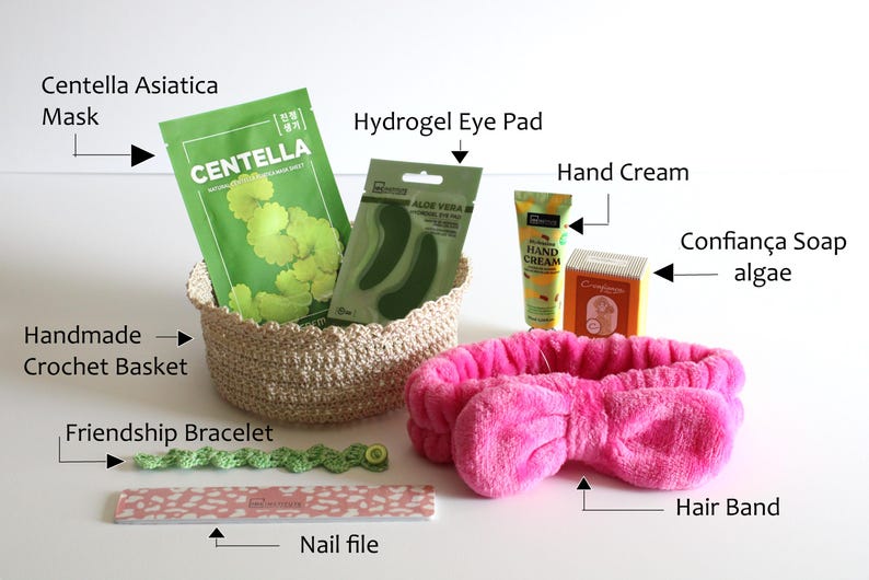 May include: A collection of self-care items including a Centella Asiatica mask, hydrogel eye pads, hand cream, and a pink hair band. A handmade crochet basket holds the skincare products. Also included are a friendship bracelet and a nail file.