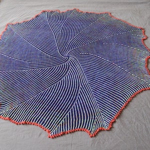 May include: A blue and white crocheted shawl with a swirling pattern and a coral-colored border.