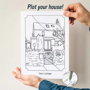 May include: A white rectangular print featuring a black line drawing of a house with the text Plot your house! at the top and Telyn Cottage at the bottom. The illustration depicts a cottage with a stone wall, a gate, and a chimney.