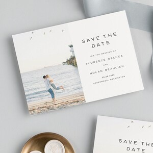 May include: Save the date card with a photo of a couple on a beach with a pier in the background. The text on the card reads "Save the Date" for the wedding of Florence Deluca and Nolan Beaulieu on 09.06.2028 in Underwood, Washington.