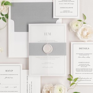 May include: A wedding invitation suite with a gray envelope, white cardstock, and a wax seal. The invitation features the couple's monogram "HM" and the text "Reception" and "Details".