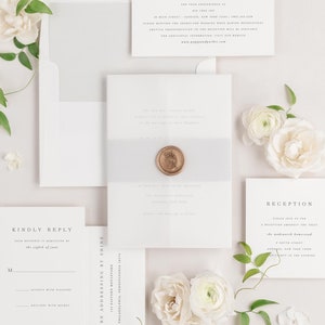 Poppy invitation flat lay with soft gray envelope liner, soft gray belly band, translucent vellum jacket, and gold wax seal.