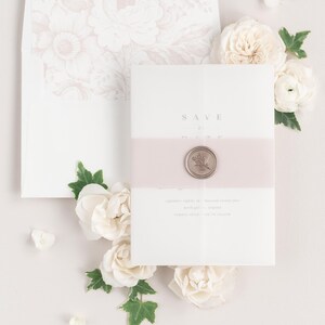 Zarah save the dates with a vintage blush belly band, translucent vellum jacket, and bronze wax seal.