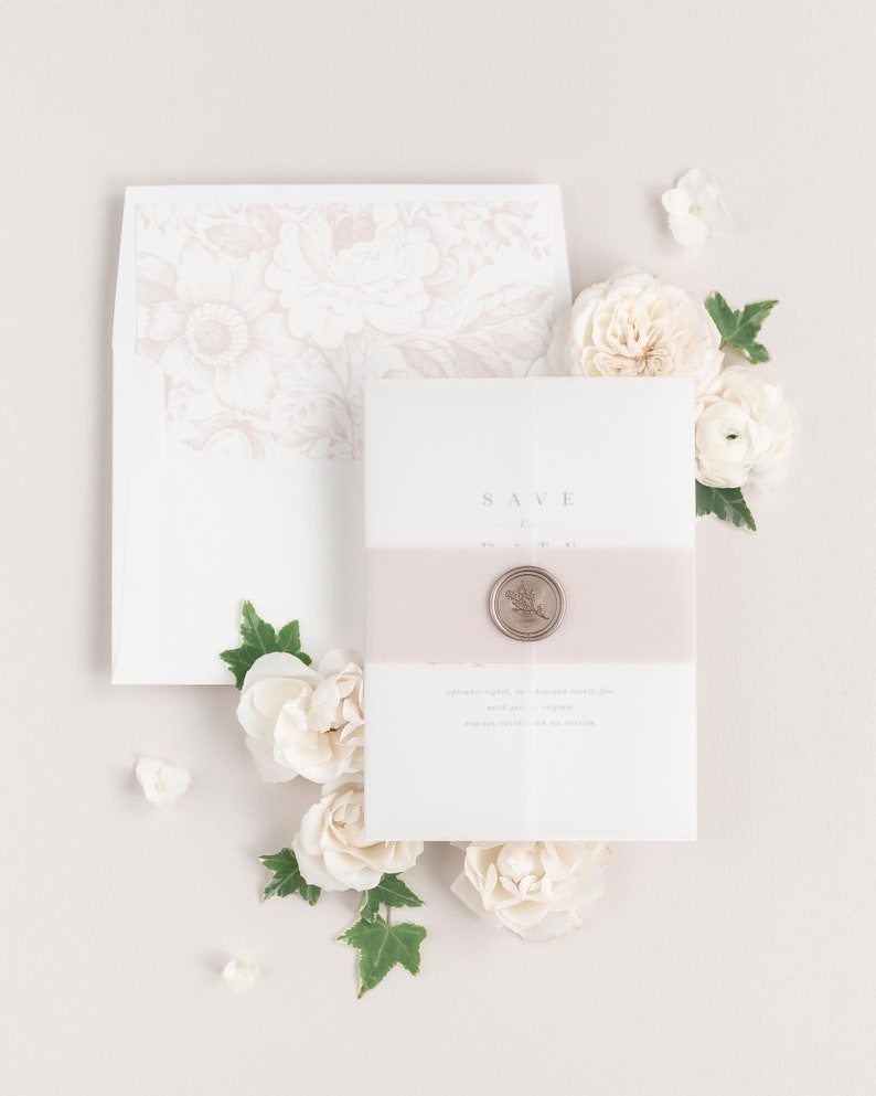 Zarah save the dates with a vintage blush belly band, translucent vellum jacket, and bronze wax seal.