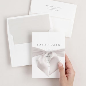 Bride holding Poppy save the date tied with mink ribbon.
