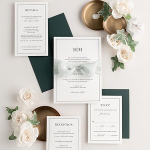 Glam Monogram invitation styled with laurel ribbon and pine envelopes.
