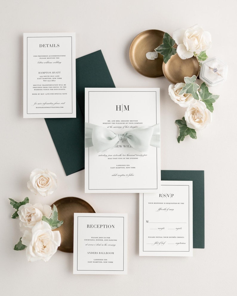 Glam Monogram invitation styled with laurel ribbon and pine envelopes.