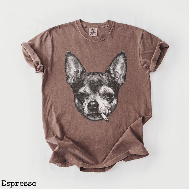 May include: Espresso-coloured t-shirt with a black and white illustration of a Chihuahua smoking a cigarette. The shirt has a vintage appearance. The word "Espresso" is printed at the bottom of the image.
