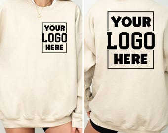 May include: Cream-colored sweatshirt with the text "YOUR LOGO HERE" in a black box on the front and back. The sweatshirt is a neutral color, suitable for custom branding or personal design.