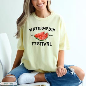 Pu&ograve; includere: T-shirt giallo chiaro con la scritta nera "WATERMELON FESTIVAL" e una grafica di due fette di anguria. La maglietta &egrave; a maniche corte e di stile casual.