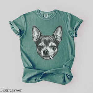 May include: Light green t-shirt with a black and white illustration of a Chihuahua smoking a cigarette. The t-shirt has a crew neck and short sleeves. The text "Lightgreen" is at the bottom of the image.
