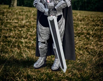 May include: A person in silver armor stands in a grassy field, holding a large, two-toned sword. The armor has detailed plating, and a black cape drapes down the back. The sword is approximately 48 inches long.