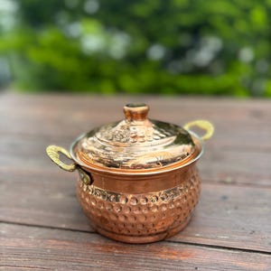 Könnte beinhalten: Ein Set aus drei Keramikbechern mit gesprenkelter, matter Oberfläche. Die Becher sind in Creme-, Hellgrau- und Dunkelgrautönen gehalten. Jeder Becher hat ein schlichtes, minimalistisches Design und einen abgerundeten Henkel.