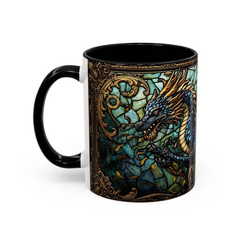 May include: A ceramic mug with a black handle and interior, featuring a wrap-around design of a blue and gold dragon set against a teal and green stained glass background with intricate gold filigree borders framing the mythical creature.
