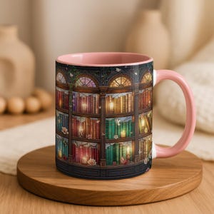 Peut inclure: Un mug en c&eacute;ramique avec un int&eacute;rieur et une anse rose pastel, orn&eacute; d'une illustration enveloppante d'une biblioth&egrave;que en bois &agrave; plusieurs niveaux remplie de livres color&eacute;s, de bougies allum&eacute;es et de petites fleurs blanches.