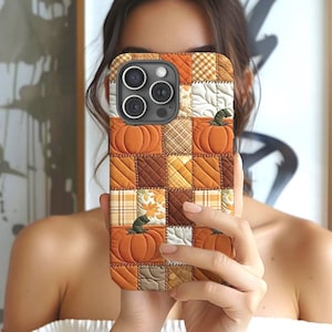 May include: A phone case featuring a patchwork design with orange pumpkins and various autumn-themed patterns. The case has a quilted appearance with a mix of orange, brown, and yellow squares, creating a fall harvest theme.