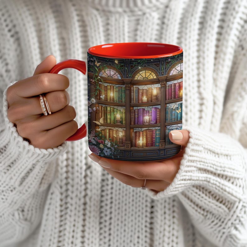 Peut inclure: Un mug en c&eacute;ramique avec un int&eacute;rieur et une anse rouge vif, orn&eacute; d'un motif enveloppant repr&eacute;sentant une biblioth&egrave;que en bois &agrave; plusieurs niveaux remplie de livres color&eacute;s, de bougies allum&eacute;es et de fleurs sur le c&ocirc;t&eacute; gauche ext&eacute;rieur.