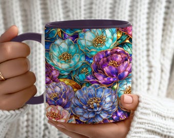Può includere: Una tazza in ceramica con manico e interno viola, con un vivace motivo floreale. I fiori sono nelle tonalità del blu, del viola e del rosa, delineati in oro. La tazza è tenuta da una persona che indossa un maglione bianco.